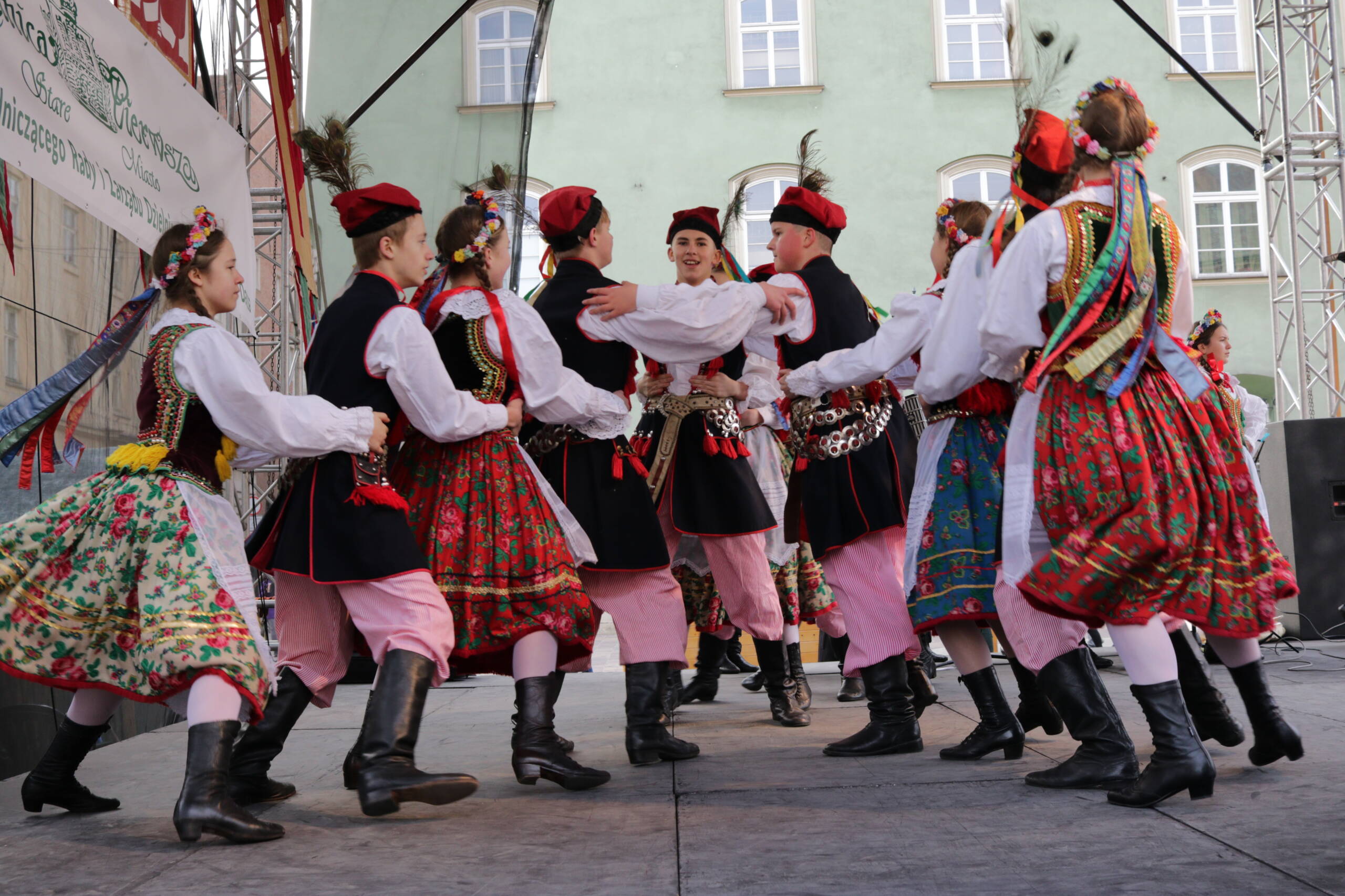 Young dancers in Kraków-region folk costume performing a circle dance on an outdoor stage