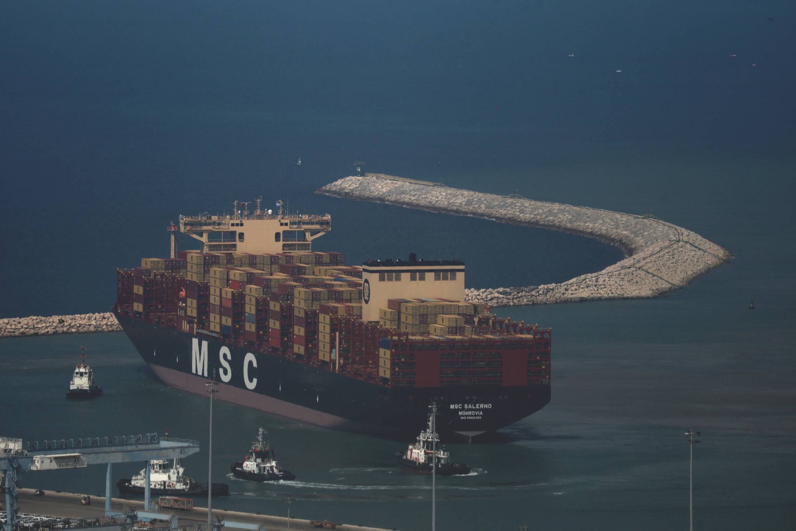 Container ship under tug escort approaching a harbour breakwater