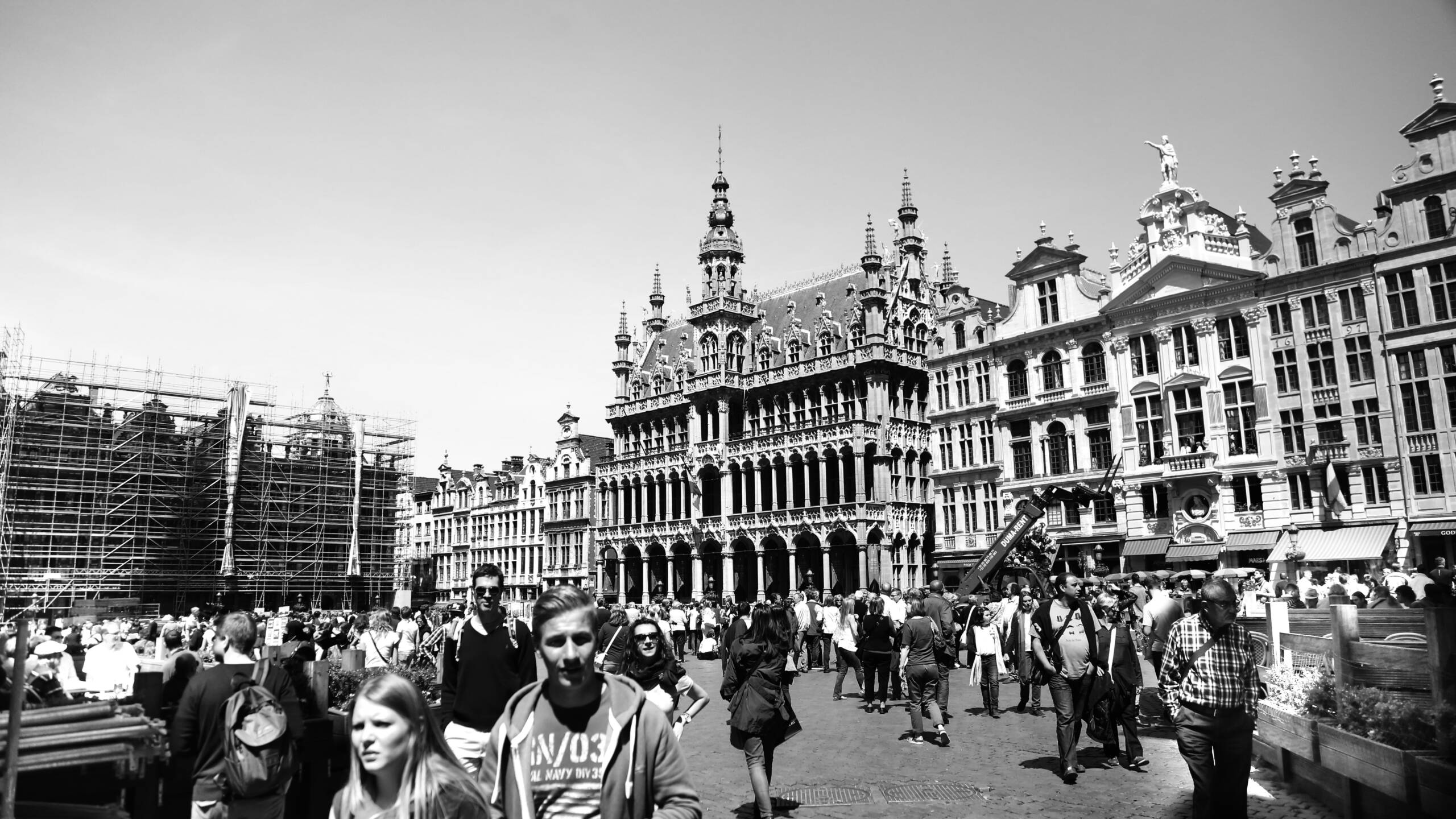 Crowds walking across the Grand Place in Brussels with its ornate guild houses behind
