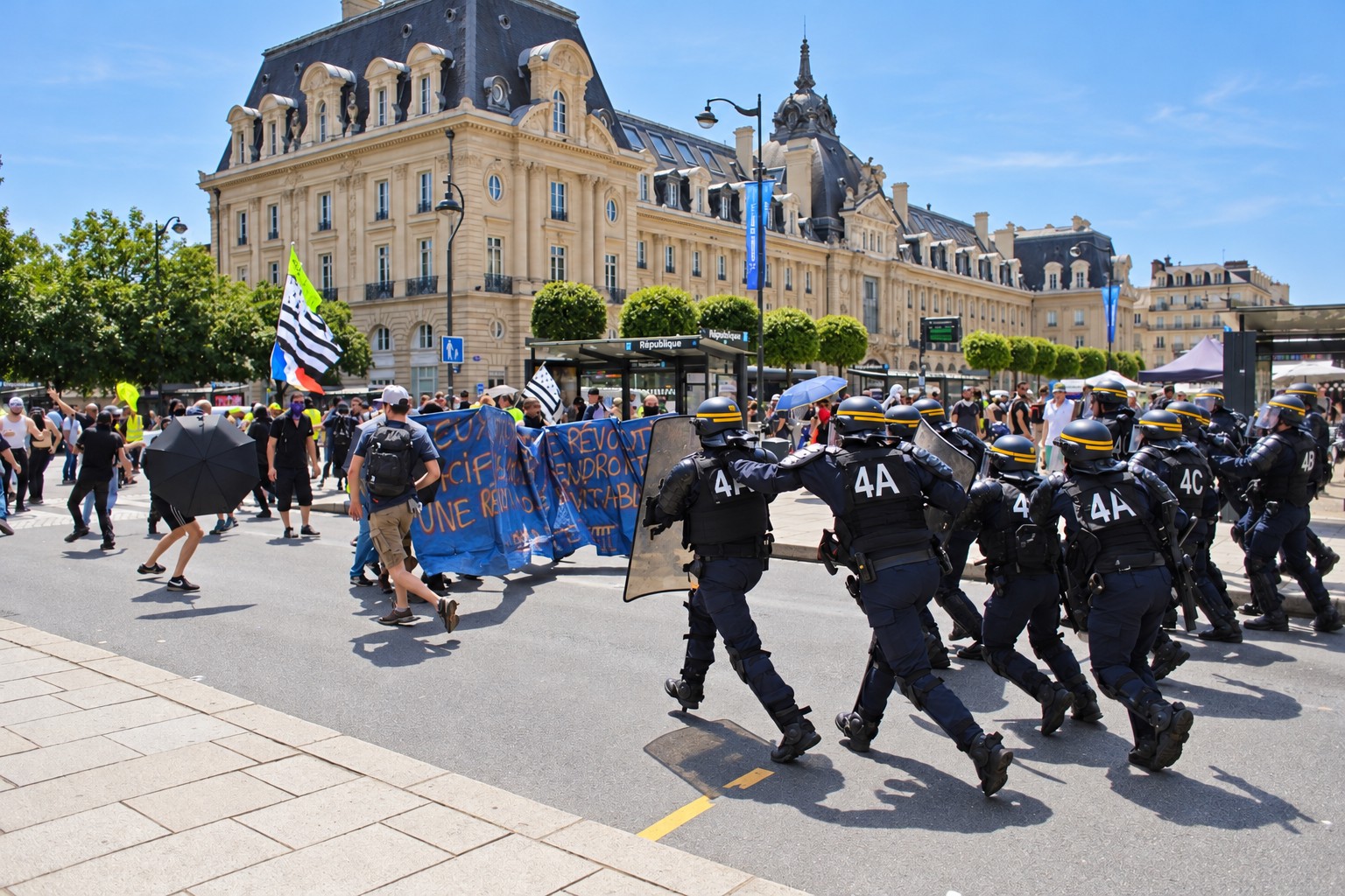 Riot police with helmets and shields move across a sunlit square facing demonstrators with blue banners and a Breton flag, beneath an ornate cream facade.