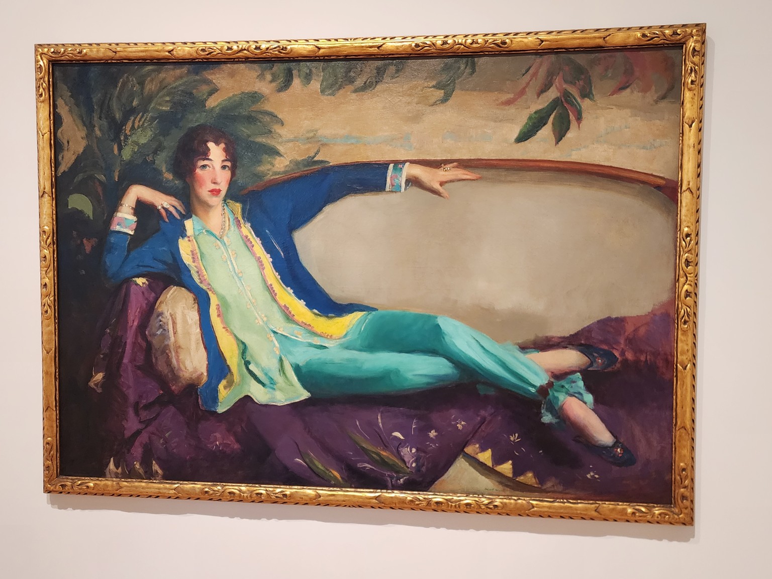 Robert Henri's 1916 portrait of Gertrude Vanderbilt Whitney reclining in a blue jacket and turquoise trousers on a purple sofa